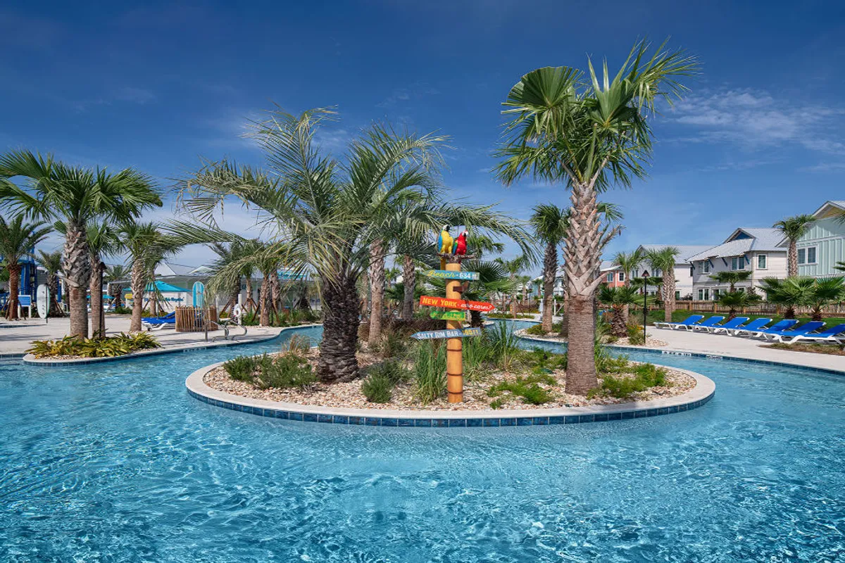 A vibrant, tropical scene featuring a crystal-clear lazy river winding through lush palm trees and greenery, with rows of blue lounge chairs lining the riverbank. A playful, colorful signpost adds a fun resort vibe, inviting guests to float and relax or participate in nearby water activities.